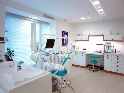 A modern, clean dental office with dental chairs, instruments, and bright overhead lighting.