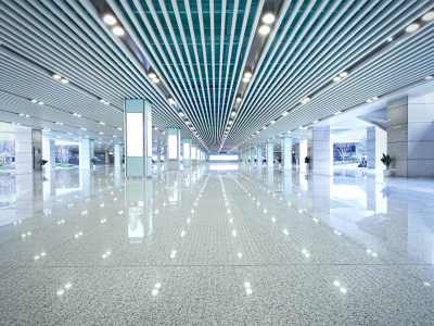 Spacious, modern indoor space with reflective floors, featuring a ceiling with linear lighting fixtures and a symmetrical design, creating a clean and futuristic atmosphere.