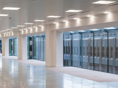 Spacious, modern hallway with large windows providing ample natural light, featuring polished floors and contemporary recessed lighting for a bright and clean look.